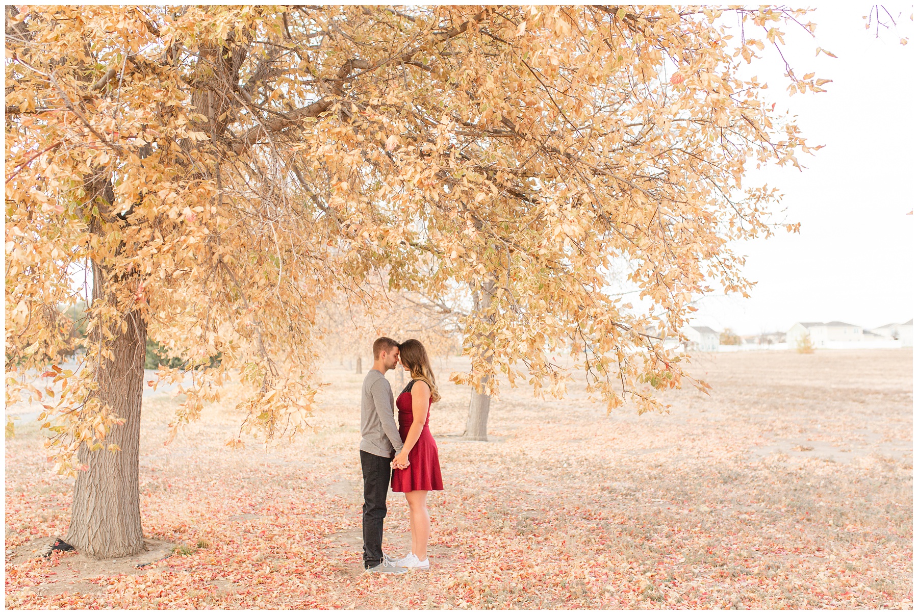 Natural light couples session couple standing under tree girl in red