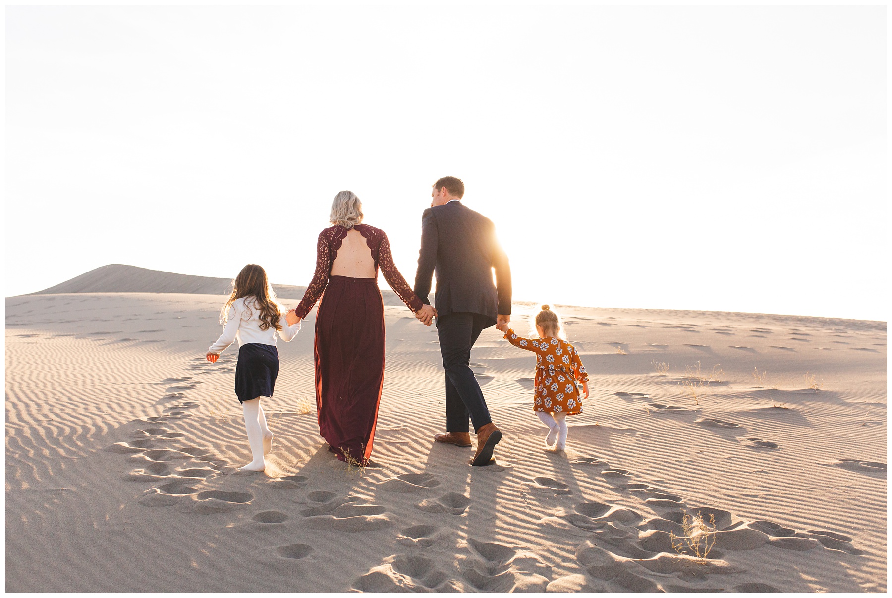 family walking away from camera on a sand dune into the sunset in Idaho
