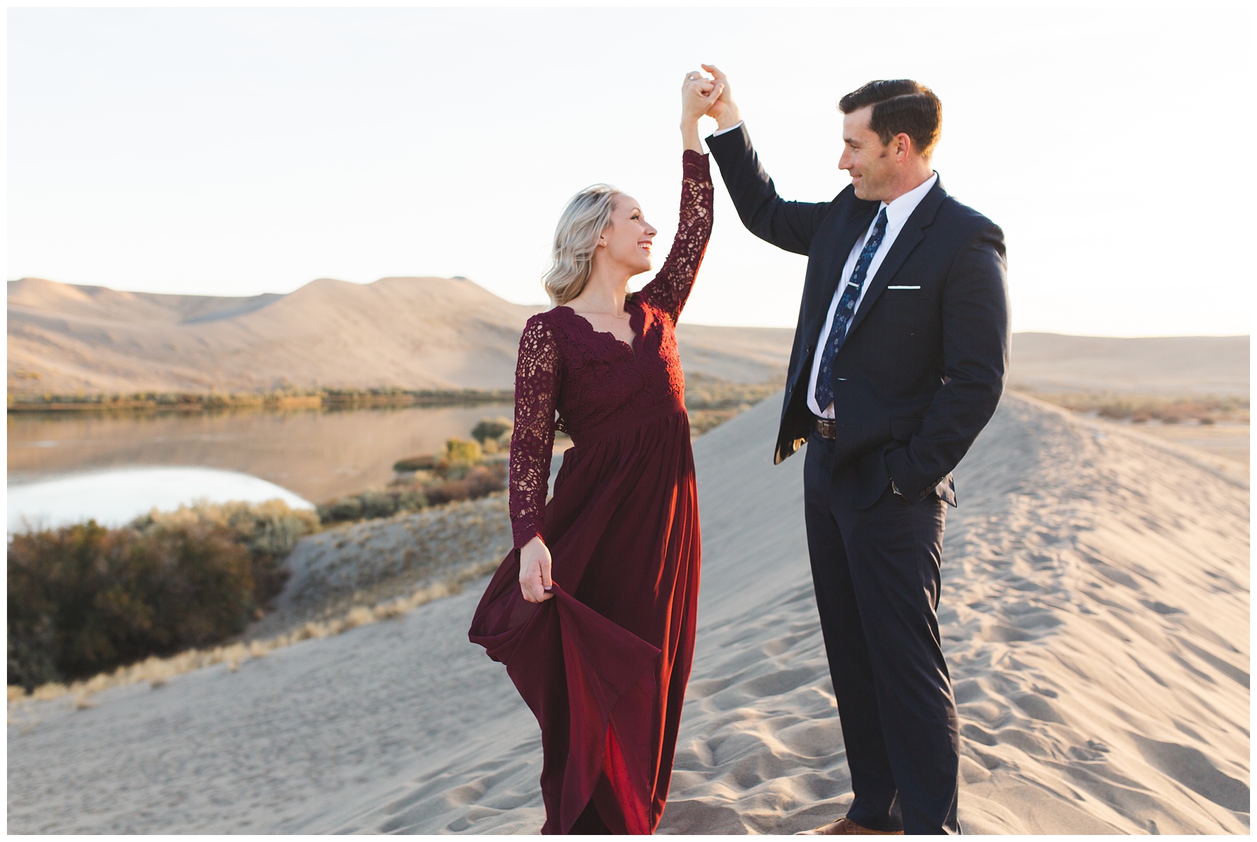 man in suit, woman in red dress dancing on the sand dunes