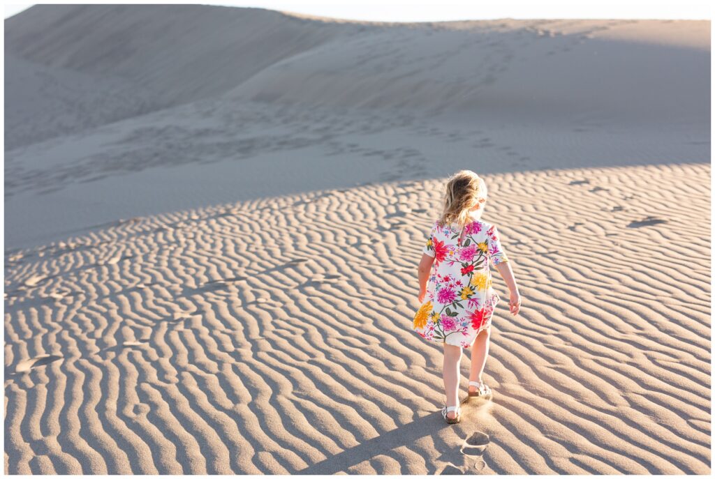 candid family photo session girl climbing sand dune in bruneau idaho