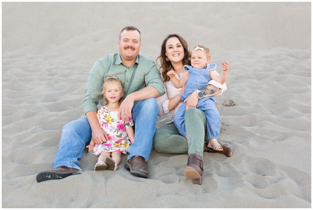 family looking and smiling at camera  sitting on a sand dune in Idaho