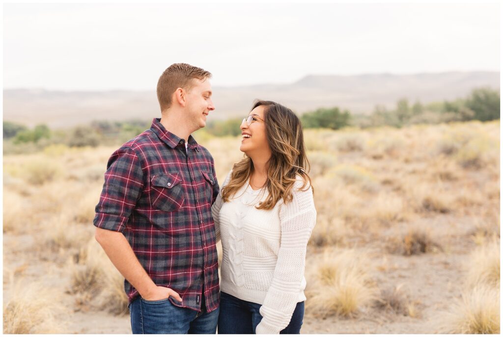 Couple in fall clothes laughing and smiling at each other in Boise Idaho Candid Engagement Photos