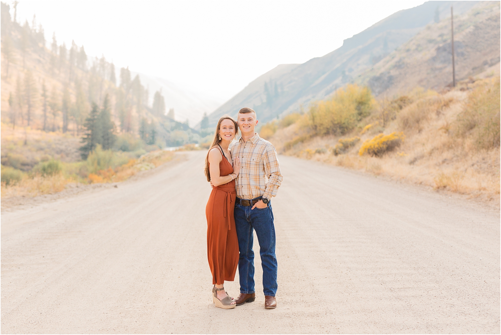 Couples' Photo Session in Pine Idaho. Wife in jumper, husband in plaid looking at camera smiling with mountains in the background.