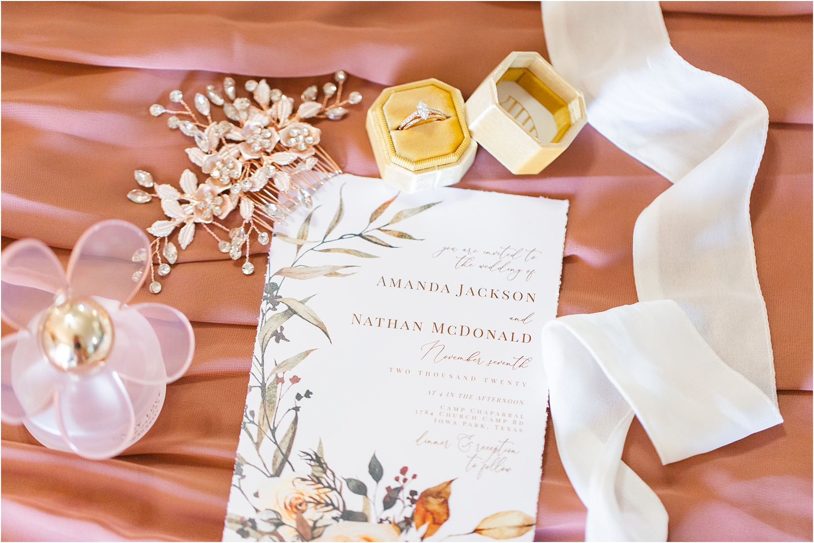 Wedding flat lay with mauve colors. includes wedding invitation, perfume, wedding rings, hair piece, ribbon. Miranda Renee Photography Boise Idaho