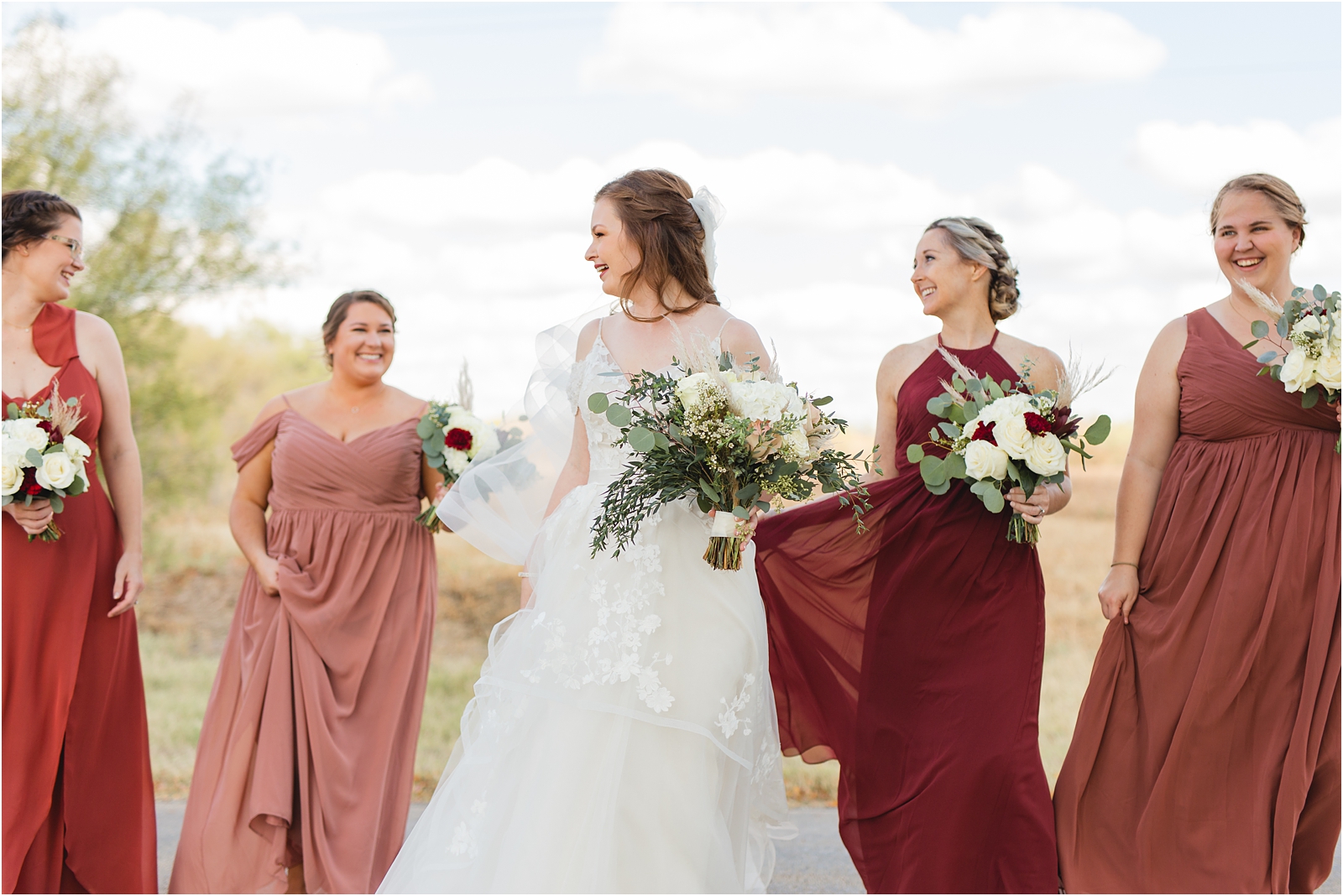 bride smiling, looking at her bridesmaids dressed in mauve, and dusty pink. Miranda Renee