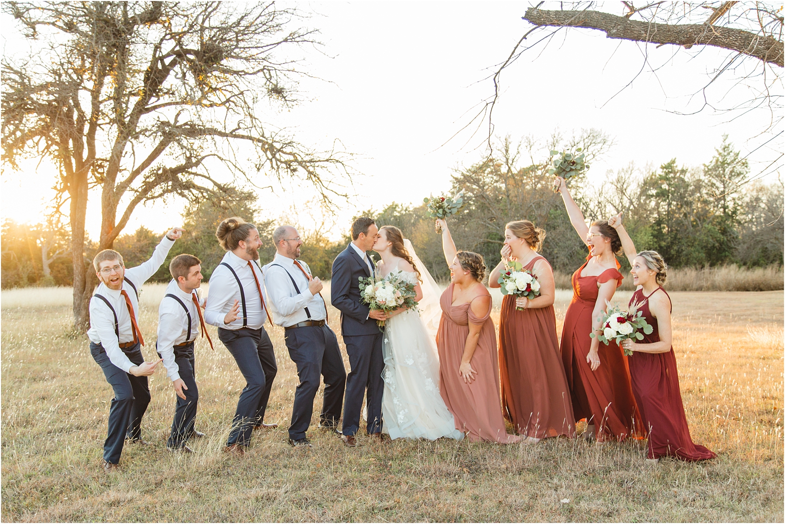 bridal party celebrating while the bride and groom kiss in Boise Idaho. Photo by Miranda Renee Photography