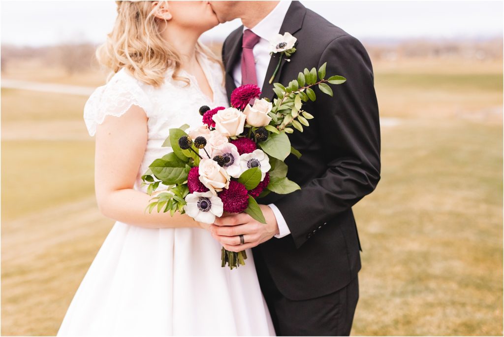Married couple kissing and holding bridal bouquet of flowers in Boise Idaho