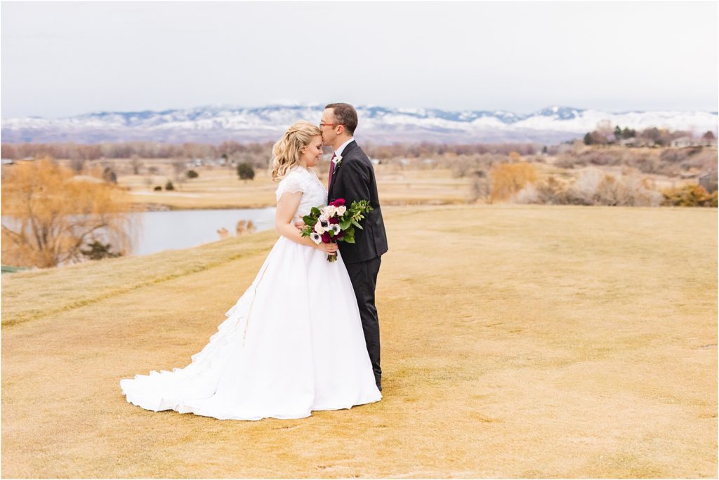 Photo by Miranda Renee Photography. groom kissing bride's forehead with Idaho mountains in the background