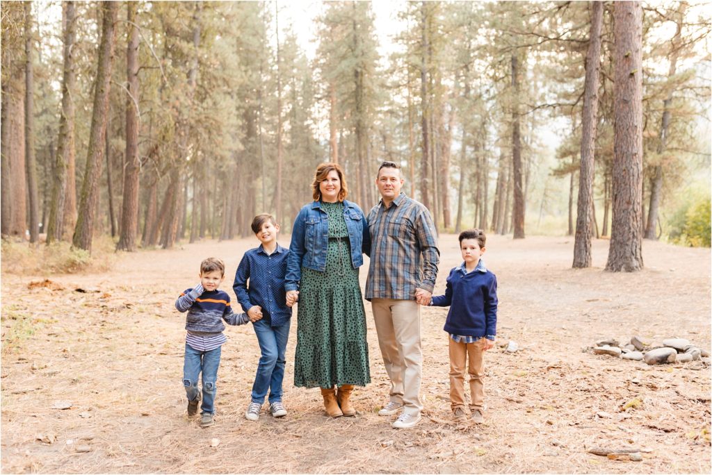 family looking at the camera holding hands in the woods photo by Miranda renee photography