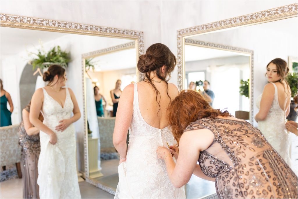 mother of bride buttoning bride's dress in the bridal suite Wedding at 1st miracle