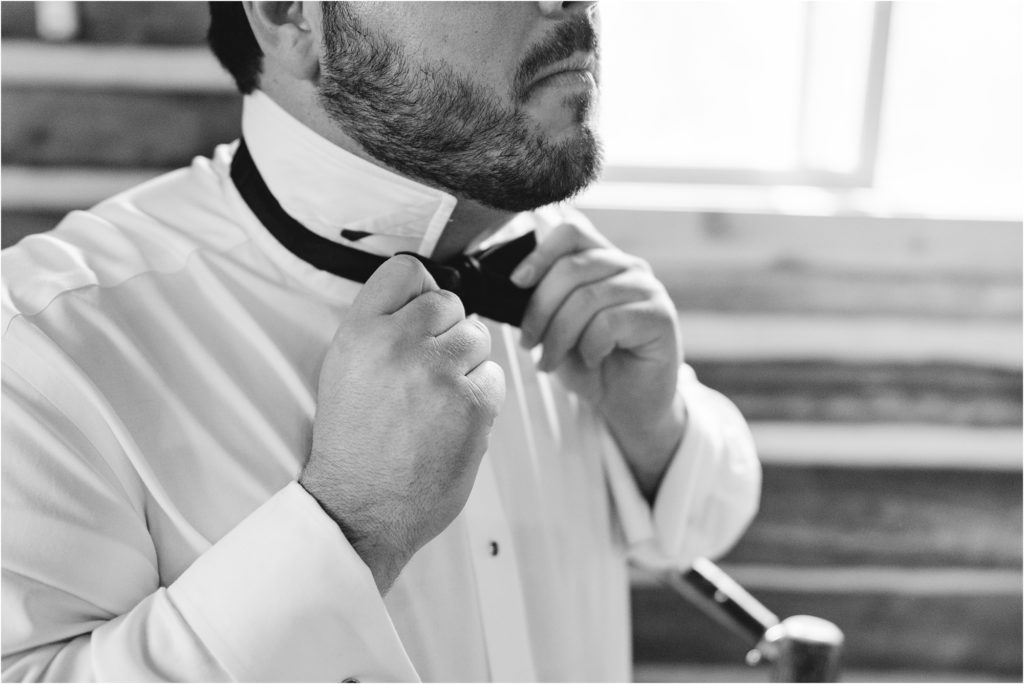 black and white image of groom tying tie
