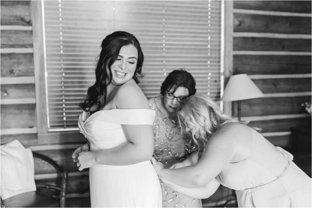 bride's mom and maid of honor getting bride into dress Wedding at Redfish Lake Lodge