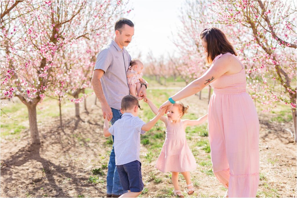 family doing ring-around-the-rosie in a blooming orchard in idaho