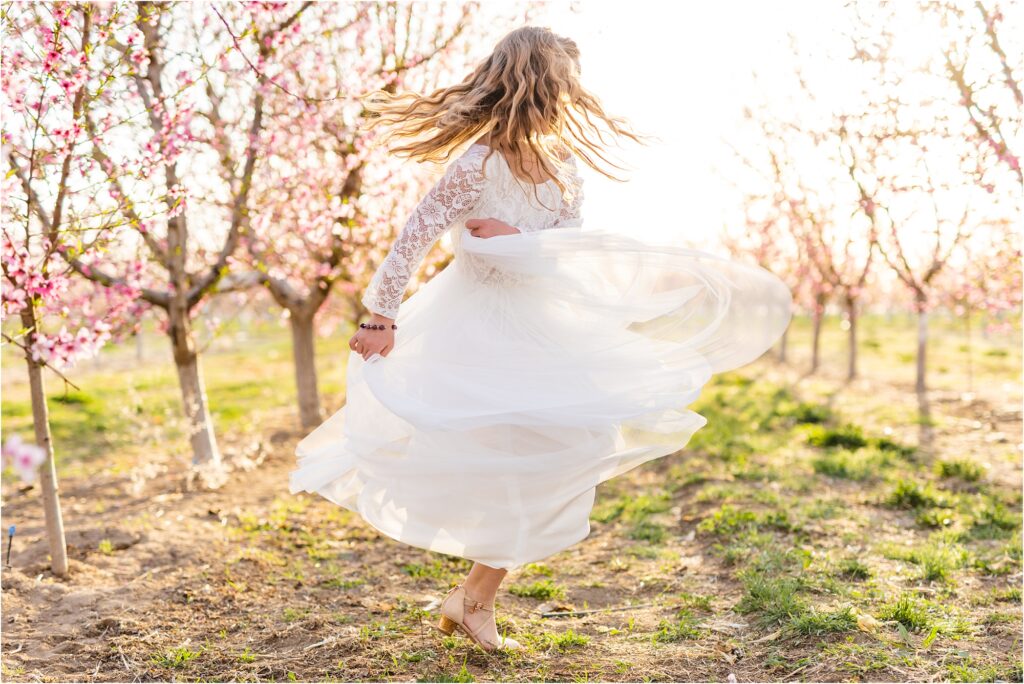 girl twirling her dress in the setting sun in a blooming orchard in Idaho