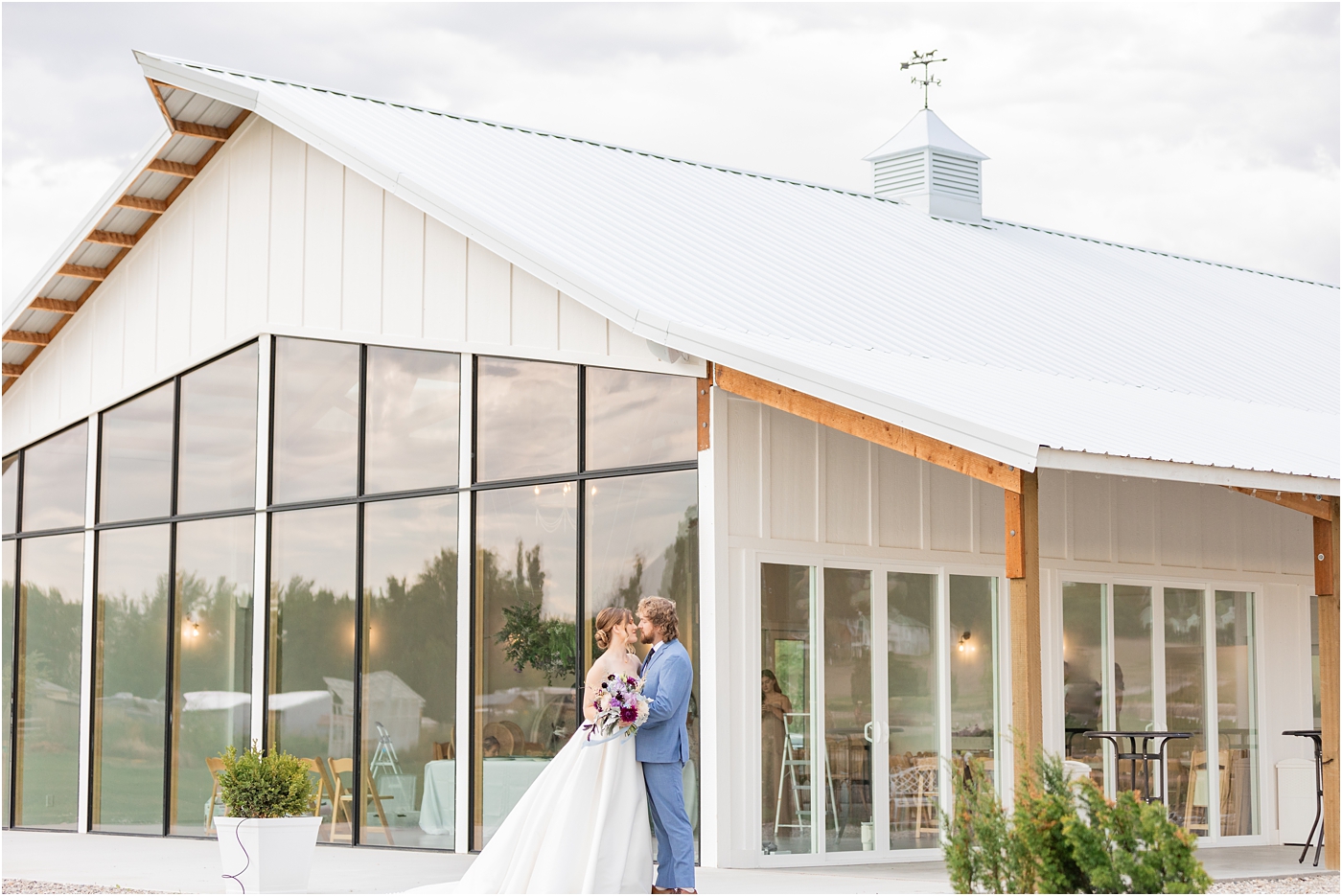 bride and groom standing in front of white wedding venue