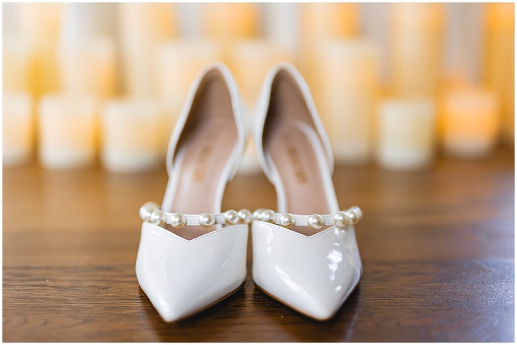 ivory wedding shoes with pearls in front of candles