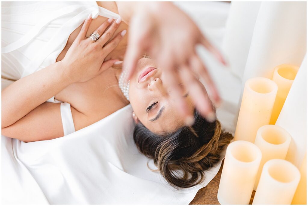 bride laying on her back with her hand extended toward the camera blocking part of her face