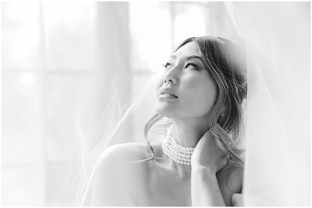 black and white photo of bride under her veil looking up at the sky