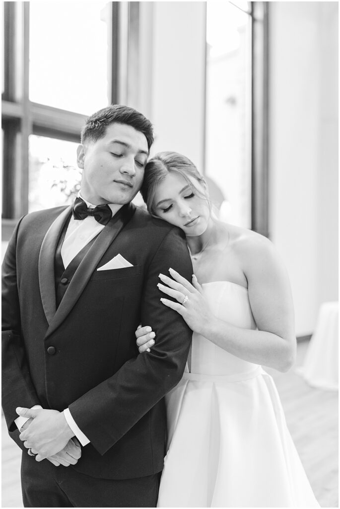 Black and white image of bride leaning on grooms shoulder 