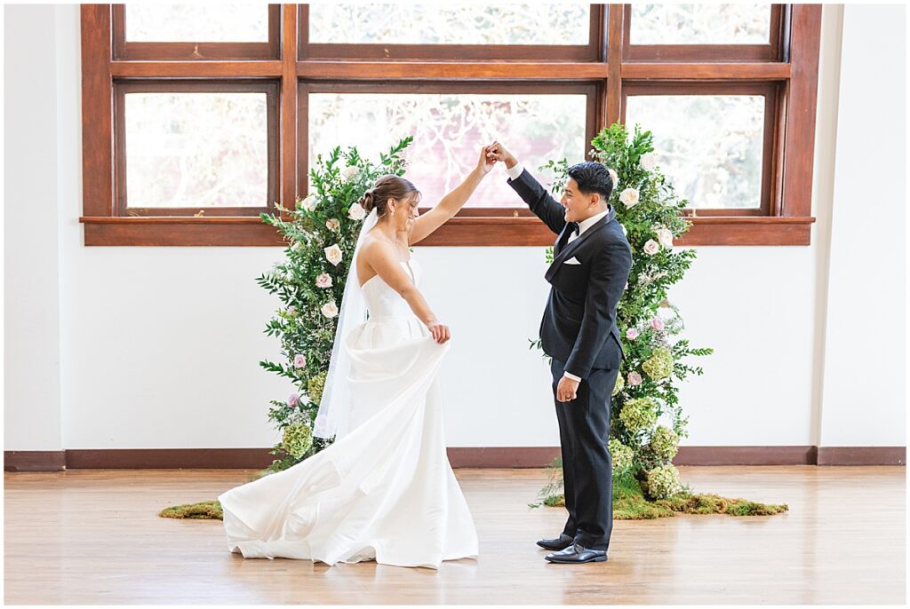 groom twirling bride in front of broken floral arch at the TRICA Boise