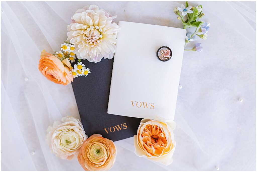 bride and groom vow books on top of pearl-studded veil
