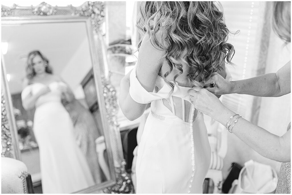 bride's mom buttoning up bride's dress