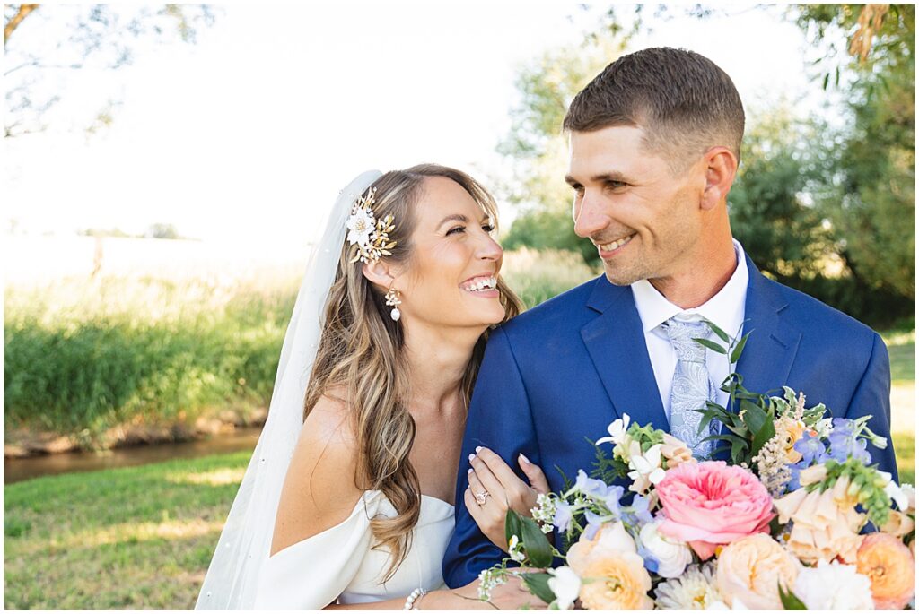 bride holding grooms arm, looking at each other and smiling